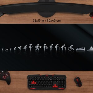 May include: A black mouse pad with a graphic depicting the stages of life, from infancy to old age, and death. The mouse pad measures 36x15 inches. A keyboard, mouse, and game controller are visible.