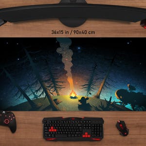 Pode incluir: Um tapete de rato para jogos azul escuro e preto com uma cena de noite estrelada com uma fogueira no centro. O texto "36x15 in / 90x40 cm" está impresso no tapete.