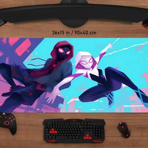 May include: A rectangular mouse pad featuring two comic book characters in action poses. The pad is 36x15 inches and displays a vibrant illustration with a blue and pink background. A keyboard, mouse, and controller are visible.