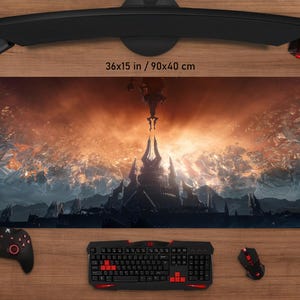 May include: A large rectangular gaming mouse pad, 36x15 inches, featuring a fantasy landscape with a castle and a fiery sky. The pad is surrounded by gaming accessories, including a keyboard, mouse, and controller.