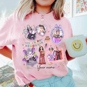 Op de afbeelding: Roze T-shirt met cartoon illustraties van Disney schurken, een verjaardagstaart en de tekst "It's my birthday". Het shirt bevat de tekst "Your name" en het nummer 4. Een witte mok met een smiley wordt in de afbeelding vastgehouden.
