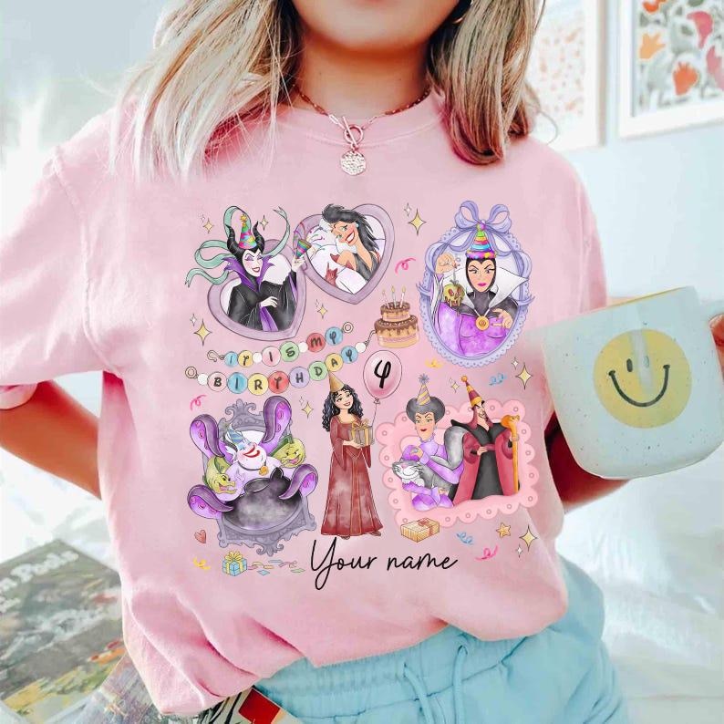 Op de afbeelding: Roze T-shirt met cartoon illustraties van Disney schurken, een verjaardagstaart en de tekst "It's my birthday". Het shirt bevat de tekst "Your name" en het nummer 4. Een witte mok met een smiley wordt in de afbeelding vastgehouden.