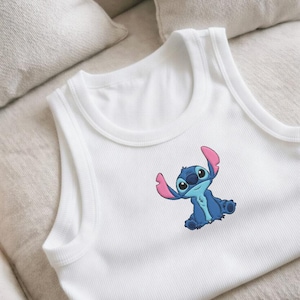 Puede incluir: Camiseta sin mangas blanca con dise&ntilde;o de personaje de dibujos animados azul. El personaje tiene orejas grandes y est&aacute; sentado con los brazos levantados. La camiseta sin mangas es de material suave y acanalado, adecuada para uso casual.