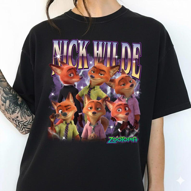 Puede incluir: Camiseta negra con un dise&ntilde;o de Nick Wilde de Zootopia. El dise&ntilde;o incluye el texto "NICK WILDE" en fuente morada y dorada sobre un grupo de zorros de dibujos animados. La palabra "Zootopia" est&aacute; en verde en la parte inferior.