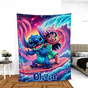 May include: A vibrant blanket featuring a colorful illustration of Stitch and Lilo surfing a wave. The blanket has a pink, blue, and purple color scheme with the name "Oliva" at the bottom. The design is reminiscent of a tropical paradise.