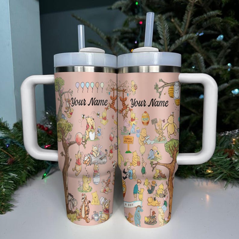 May include: Two pink insulated tumblers with white handles and lids, featuring illustrations of Winnie the Pooh characters. Each tumbler has a straw and the text "Your Name". The design includes trees, balloons, and various characters.