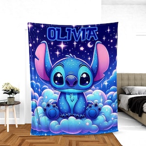 May include: A blue blanket with a cartoon character design, large eyes and ears, sitting on clouds. The blanket has the name "OLIVIA" in blue letters against a starry night sky background.