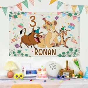 May include: A birthday banner with Lion King characters, including Simba, Timon, and Pumbaa, the number 3, and the name "Ronan." The banner is decorated with confetti, presents, and green vines. A party scene with a cake and balloons.