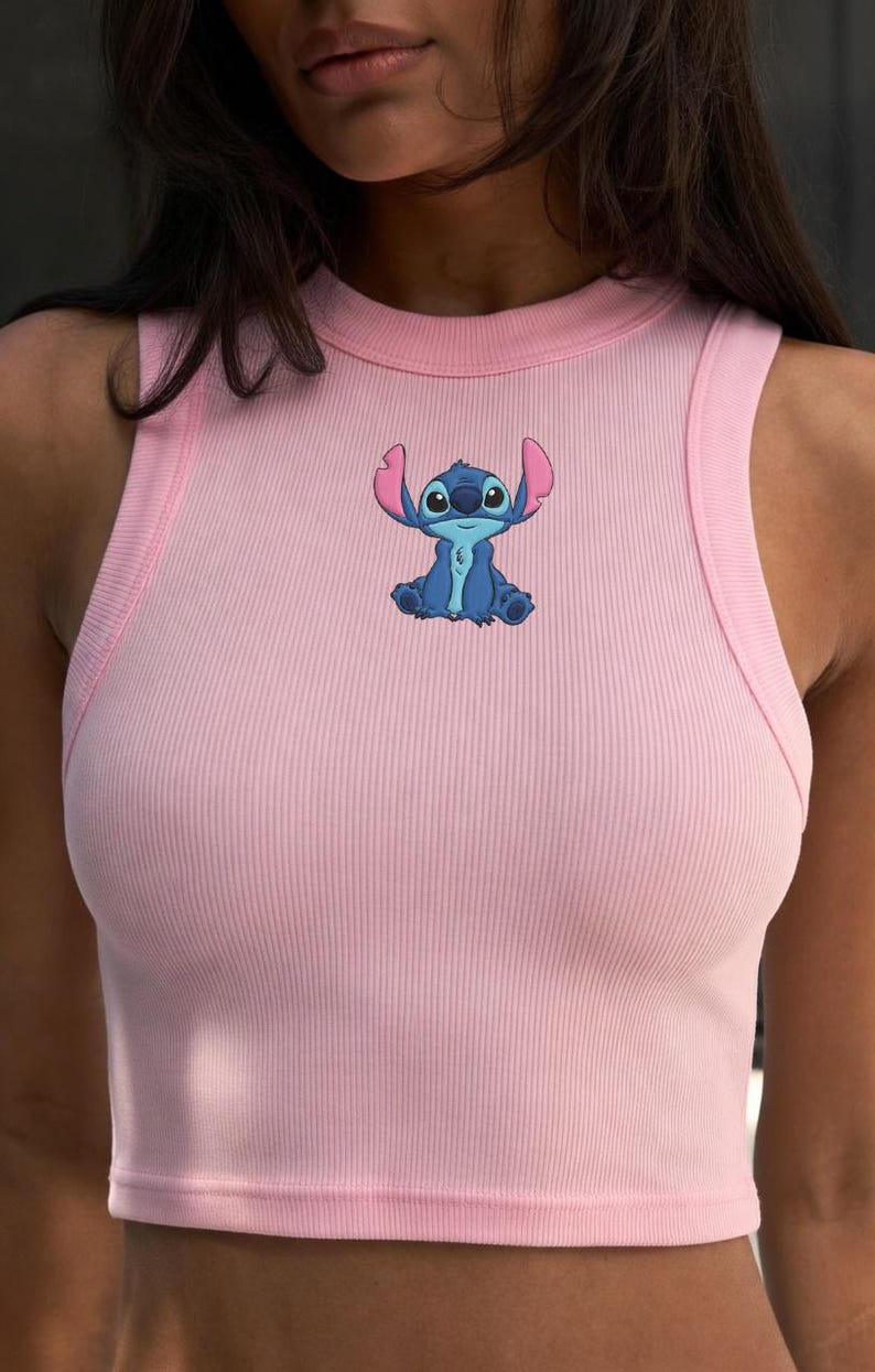 Puede incluir: Top corto rosa p&aacute;lido con costuras acanaladas y un personaje de dibujos animados azul. El top sin mangas tiene un cuello redondo y una silueta ajustada. El personaje est&aacute; en el centro.