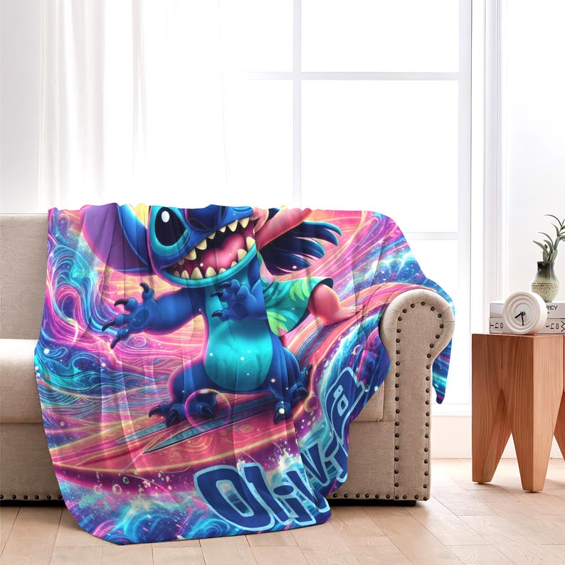 May include: A colorful throw blanket featuring a cartoon character in shades of blue, pink, and purple. The design includes the character surfing on a board with the word "Ohana" visible. The blanket is draped over a beige sofa.