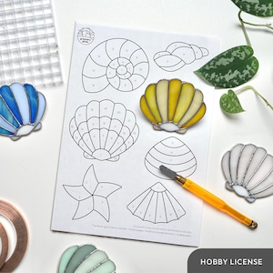 Op de afbeelding: Een glas-in-lood-knutselset met verschillende zeethema-patronen, waaronder schelpen, een zeester en een nautilus. De set bevat een bedrukt patroonblad met genummerde secties, een set glazen stukken en instructies voor het assembleren van het project. De set is perfect voor beginners en ervaren knutselaars.