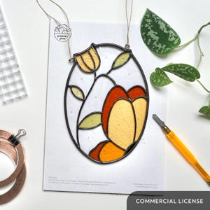 Op de afbeelding: Een glas-in-lood-set met een bloemmotief met gele, oranje en groene glasstukken. De set bevat een patroon met genummerde secties en een glascutter.