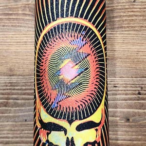May include: A colorful water bottle featuring a vibrant, psychedelic design. The design includes a stylized skull with radiating lines in shades of yellow, orange, red, and blue against a black background. The bottle has a black lid.