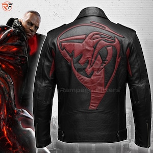 Könnte beinhalten: Schwarze Lederjacke mit rotem Grafikdesign auf dem Rücken. Die Jacke hat einen klassischen Biker-Stil mit einem Reverskragen, Schulterklappen und einem Reißverschluss. Das rote Design scheint eine stilisierte Schlange oder ein Drache zu sein.