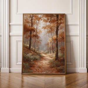Könnte beinhalten: Gerahmtes Landschaftsgemälde eines Waldweges im Herbst. Das Kunstwerk zeigt einen Pfad, der sich durch Bäume mit orangefarbenen und braunen Blättern schlängelt. Das Gemälde hat einen goldenen Rahmen und wird vor einer weißen Wand ausgestellt.