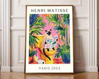以下が含まれることがあります： 「HENRI MATISSE PARIS 1953」の文字が入った額装されたアートプリント。黄色いトイレで新聞を読むシャム猫が描かれています。植物に囲まれ、ピンク、緑、青の明るい色使いで、活気のある室内シーンを作り出しています。