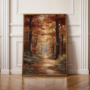 May include: A framed painting of a forest scene in autumn. The artwork shows a path through trees with orange and red leaves. The painting is set in a gold frame, evoking a sense of warmth and the changing seasons.