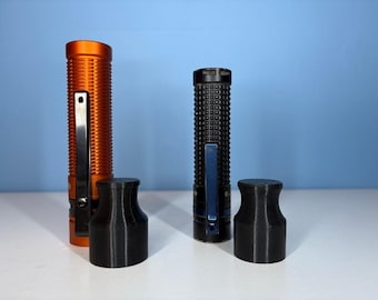May include: Two flashlights, one orange and one black, with black pocket clips, and two black cylindrical caps. The orange flashlight has a ribbed texture. The black flashlight has a textured, grid-like pattern. The caps are cylindrical with a flared top.