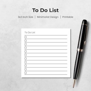 Peut inclure: Un bloc-notes To Do List blanc de 7,6 x 7,6 cm avec un design minimaliste. Le bloc-notes comporte une liste de lignes avec des cercles pour les cases à cocher. Un stylo noir avec des accents dorés est placé à droite.