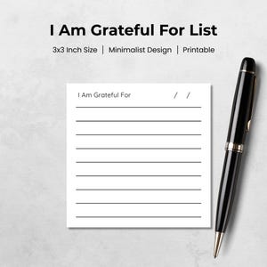 May include: A white 3x3 inch printable gratitude list with the text "I Am Grateful For" and lined spaces. A black pen with gold accents rests on the right side of the image. The design is minimalist.