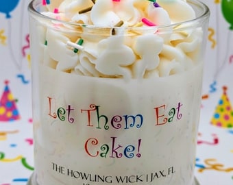 May include: A candle in a clear glass jar with white wax, topped with white frosting and colorful sprinkles. The jar has the text "Let Them Eat Cake!" in rainbow colors. The candle is 10 oz (283 g).
