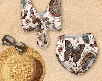 May include: A white bikini top and high-waisted bottoms with a butterfly and floral pattern in brown, blue, and tan. A straw hat and sunglasses are also in the image, suggesting a beach theme.