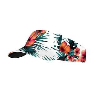 May include: White visor with a tropical floral print featuring pink, orange, and green hibiscus flowers and leaves.