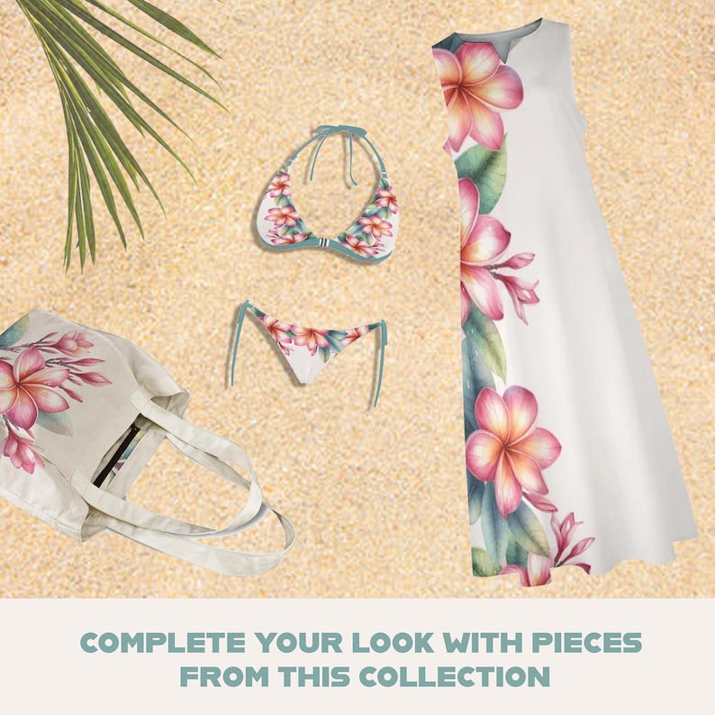 May include: A collection of beachwear including a white sundress, a bikini, and a tote bag, all adorned with a floral print in shades of pink and white. The items are arranged on a sandy surface, with a palm frond in the background.