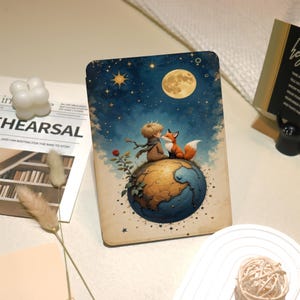 May include: A book cover with a charming illustration of a boy and a fox perched on a globe, set against a starry night sky and a full moon. The design has a vintage, storybook style with a soft colour palette.