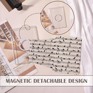 May include: Clear rectangular phone case with a white ring grip, and a patterned insert featuring black cat silhouettes on musical notes. The text "MAGNETIC DETACHABLE DESIGN" is visible at the bottom.