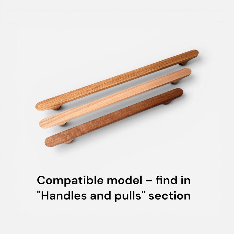 May include: Three wooden cabinet pulls in varying shades of brown, from light to dark. The pulls are rectangular with rounded ends and are arranged diagonally against a white background. Text at the bottom reads "Compatible model - find in "Handles and pulls" section."