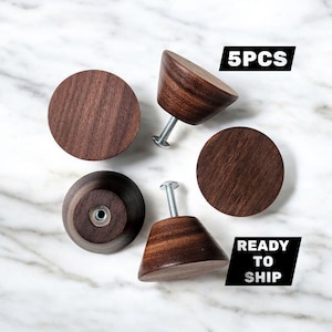 May include: Five dark brown wooden cabinet knobs, some conical and some circular, with silver screws. The knobs are arranged on a white and gray marble surface. The text "5PCS" and "READY TO SHIP" are in black boxes.