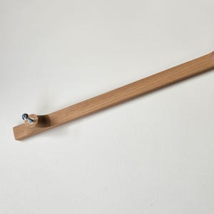 May include: A light brown wooden frame with a curved end and two silver screws. The frame is long and rectangular, with a natural wood grain finish. The frame is set against a white background.