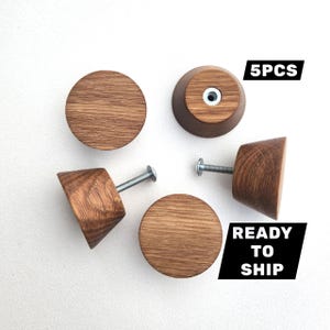 May include: Five wooden cabinet knobs with a natural wood grain finish. Each knob has a round or conical shape and includes a metal screw for installation. The image also includes the text "5PCS" and "READY TO SHIP".