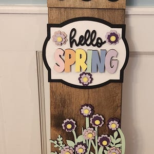 May include: Wooden spring-themed sign with a birdhouse, bird, and the words "hello SPRING." Features a yellow rain boot with flowers. The sign is approximately 36 inches tall.
