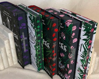 May include: Five hardcover books arranged in a row, each featuring distinct spine designs. The spines display varied illustrations including purple flowers with a sword, green vines, red flowers with an arrow, pink roses, and green fern leaves.