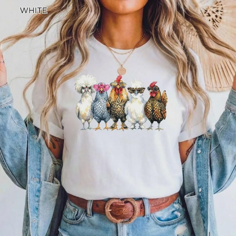 May include: A white t-shirt featuring a graphic print of five chickens standing in a row. The chickens are wearing various styles of sunglasses, including heart-shaped, round, and aviator frames. The design is centered on the chest of the shirt.
