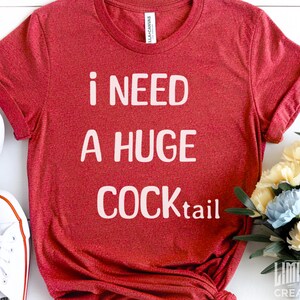 May include: Red t-shirt with white text that reads "i need a huge cocktail".