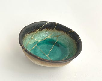Goldene Kintsugi-Verzierung auf einer smaragdgrünen japanischen Keramikschale. Ein einzigartiges Wabi-Sabi-Stück, ideal als elegantes und besonderes Geschenk.