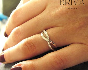 Könnte beinhalten: Ein silberner Ring mit einem gedrehten Design und kleinen Diamanten, die in die Band eingefasst sind. Der Ring befindet sich an einem Finger.