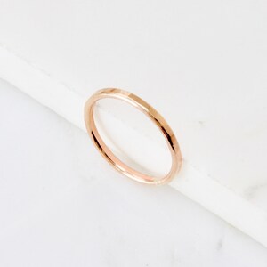 May include: A simple, thin, rose gold band ring.