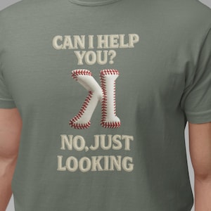 May include: A gray t-shirt with the text "CAN I HELP YOU?" above a baseball-themed graphic and the text "NO, JUST LOOKING" below. The graphic resembles the letter "K" made from baseballs.