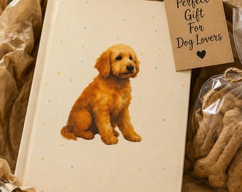 May include: A cream-colored book featuring a golden puppy illustration and small blue and yellow dots, accompanied by a brown paper gift tag with the text Perfect Gift For Dog Lovers and a heart icon, inside a box with bone-shaped dog treats.