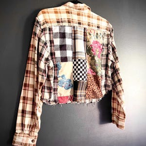 May include: A long-sleeve button-up shirt featuring a patchwork design of various fabrics including brown and white plaid, black and white buffalo check, a small black and white checkerboard pattern, floral prints, and a brown animal print.