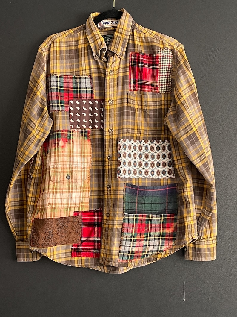 Op de afbeelding: Een button-down overhemd met lange mouwen en een geel-bruin ruitpatroon. Het overhemd heeft verschillende stoffen patches in rood, groen en bruin, waardoor een uniek patchwork-ontwerp ontstaat. De kraag heeft een label met "DANI STAR".