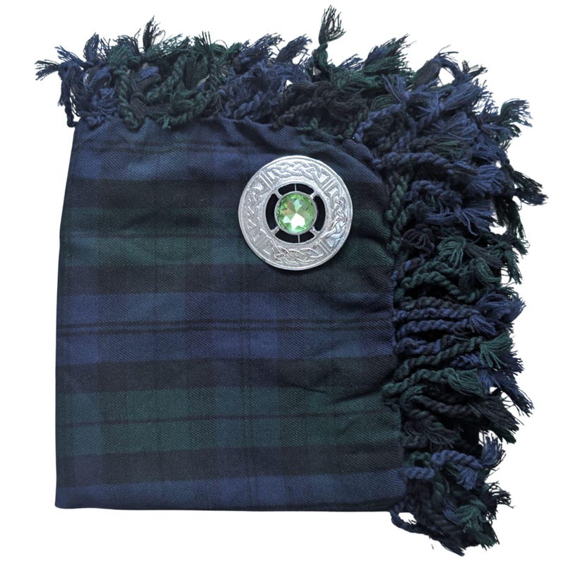 May include: A tartan plaid sash in navy blue and green with a decorative silver brooch. The brooch has a green gemstone center and an intricate Celtic knot design. The sash has a fringed edge in navy and green.