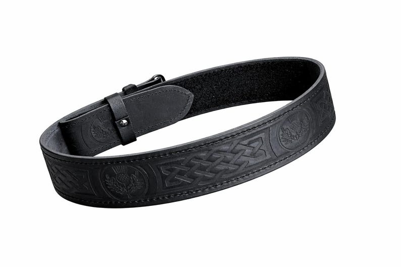 Puede incluir: Cintur&oacute;n de cuero negro con dise&ntilde;os en relieve de nudos celtas y cardos. El cintur&oacute;n tiene un cierre de hebilla y una secci&oacute;n forrada con velcro para ajustar. Un accesorio elegante.