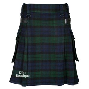 May include: A traditional kilt in a green, navy, and black plaid pattern. The kilt features leather straps with metal buckles and D-rings. The words "Kilts Boutique" are printed on the lower left side.