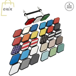 Puede incluir: Una colección de accesorios decorativos para automóviles en forma de diamante, con colores vibrantes y diseños variados. Los diseños incluyen colores lisos, rayas y la bandera estadounidense. La imagen también contiene el texto "oxix" y un logotipo "Hand Made".