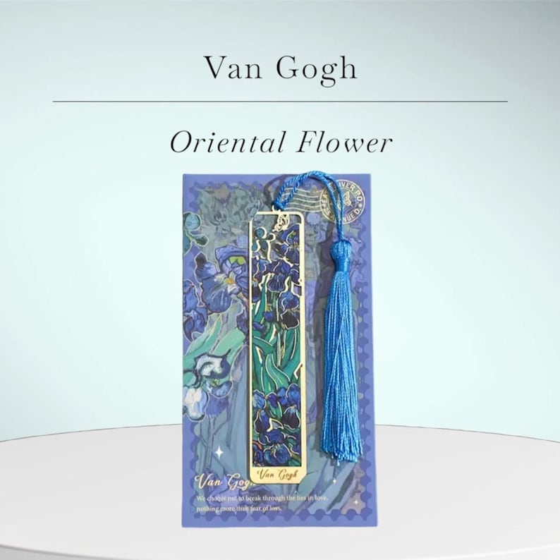 May include: A bookmark featuring a gold metal design with a blue tassel. The bookmark has a floral design with the words "Oriental Flower" and "Van Gogh" printed on it. The bookmark is on a blue background.